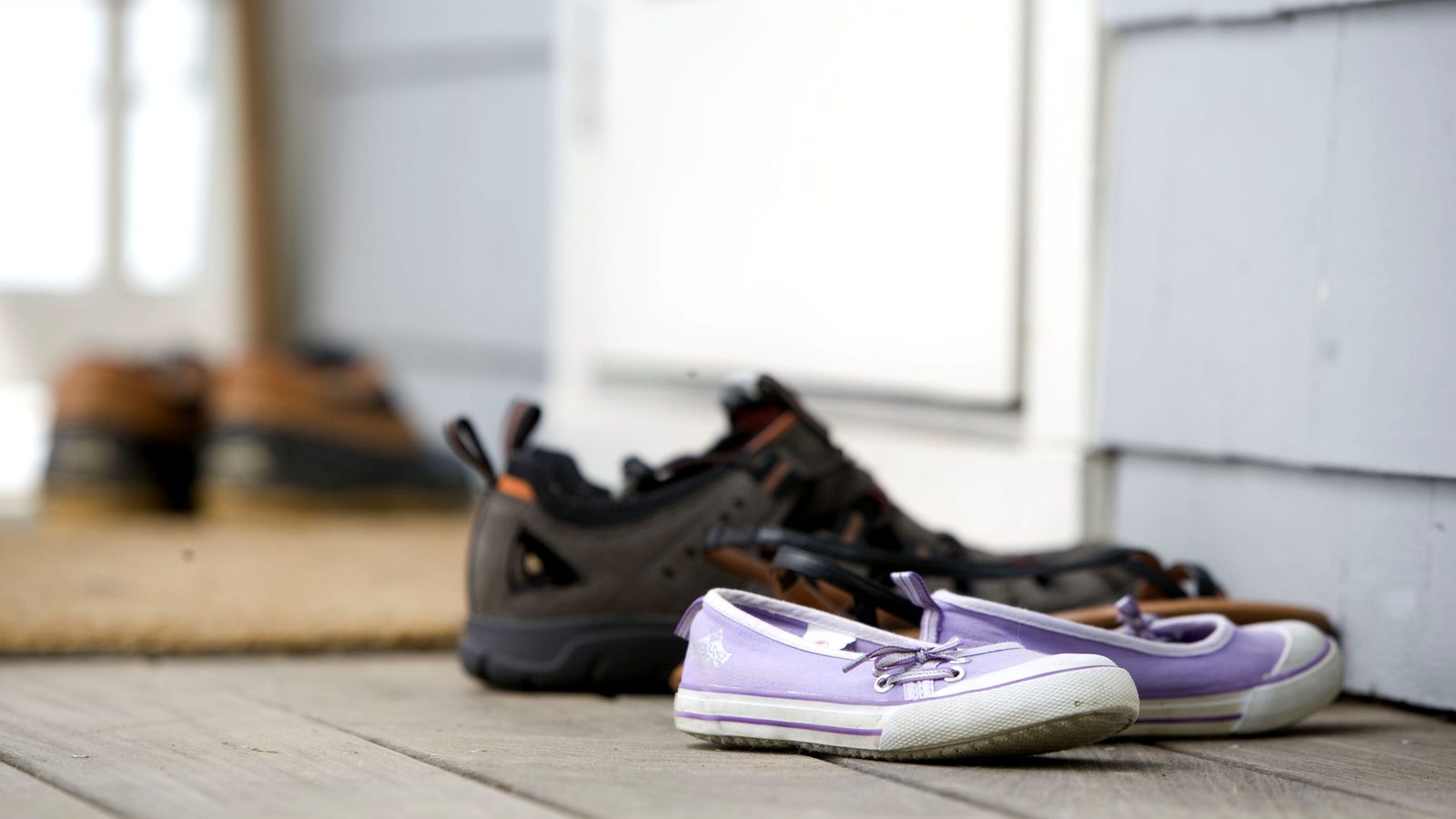 Par de sapatos de viagem deixados junto à porta de entrada da casa, sobre piso lavável, longe do quarto.